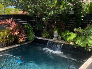 une petite piscine avec une cascade dans un jardin dans l'établissement Riverbank Guesthouse Wilton Manors, à Fort Lauderdale