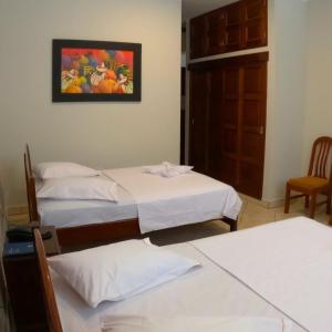 two beds in a room with a painting on the wall at Royal Park Hotel in Pucallpa