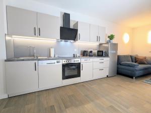 cocina con armarios blancos y sala de estar. en FeWo Urban Gotha - Apartment Orangerie - Am Schlosspark- Parken an der der Tür- Barrierefrei, 900 Meter zum Bahnhof - Wallbox, en Gotha