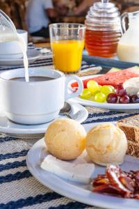 - une table avec une tasse de café et une assiette de nourriture dans l'établissement Pousada Porto Fino, à Cabo Frio