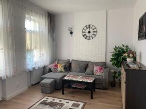 salon z kanapą i zegarem na ścianie w obiekcie Apartament blisko centrum i jeziora w mieście Giżycko