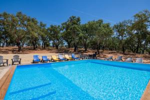 uma piscina com cadeiras e árvores ao fundo em Valle D`Água - Casas de campo em Vale de Água