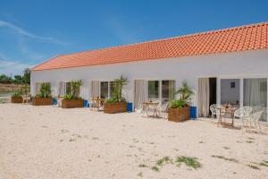 um edifício com mesas e cadeiras na praia em Valle D`Água - Casas de campo em Vale de Água