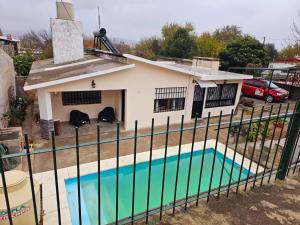 ein Haus mit Pool hinter einem Zaun in der Unterkunft LUSANYUN in Villa Carlos Paz