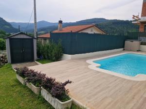 a backyard with a swimming pool and a wooden deck at Casa La Quintana in Castro-Urdiales