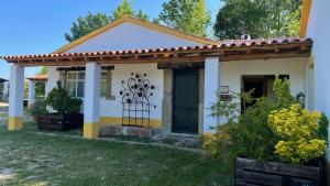 una piccola casa bianca e gialla con una porta verde di Quinta dos Trevos - Artes e Ofícios a Ladoeiro