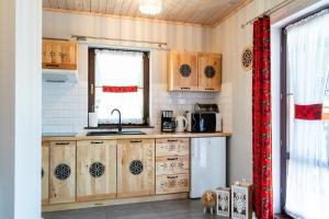 a kitchen with wooden cabinets and a refrigerator at Domki Całoroczne Osada Zbójecka Jandura in Kluszkowce