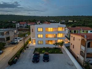 un immeuble d'appartements avec deux voitures garées dans un parking dans l'établissement Rooms & Apartments Niko, à Sukošan