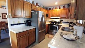 cocina con armarios de madera y nevera de acero inoxidable en Birds and Bears Retreat - On The River - Pet Friendly - WiFi - Satellite - Washer - Dryer - Large Deck - Grill - Fenced In Yard, en Red River