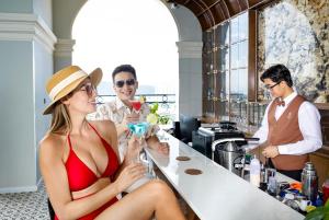 Una donna con un vestito rosso seduta al bar con un drink di Avari Hotel a Nha Trang