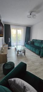 uma sala de estar com um sofá verde e uma mesa em Apartament Gabi em Giżycko