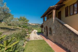 una casa in pietra con un sentiero accanto a un edificio di The Grapevine by MANVI a Montepulciano