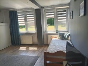 - une chambre avec deux fenêtres et un lit dans l'établissement Apartament Blekit Nieba, à Tykocin