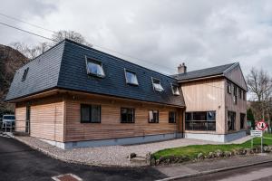 a wooden house with a black roof on a street at Glen Nevis Youth Hostel in Fort William