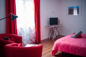 a bedroom with a red bed and a red chair and a window at hotel rural GA7COLORES only adult in Montaña Blanca