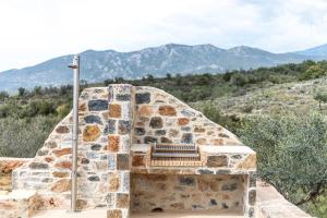 a stone fireplace with mountains in the background at Lakkos Villas in Kardamili