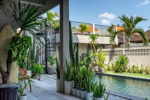 une cour avec des plantes et une piscine dans l'établissement The Breeze Stay and Surf Canggu Bali, à Canggu