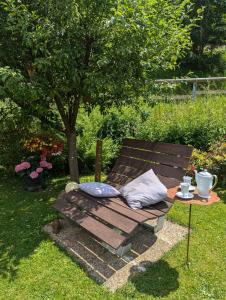 eine Holzbank mit zwei Kissen neben einem Baum in der Unterkunft Ferienwohnung Soreth in Schmallenberg