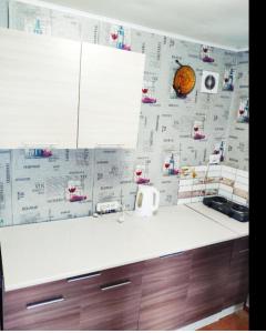 a kitchen with a white counter top with paper on the wall at Гостевой дом золотые пески in Zatoka