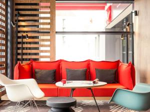 un sofá rojo en una habitación con mesa y sillas en ibis Troyes Centre, en Troyes