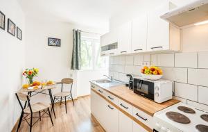 a kitchen with white appliances and a table with a bowl of fruit at Riverside Apartment No1 in Esztergom