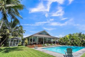 ein Haus mit einem Pool und Palmen in der Unterkunft Gorgeous Renovated 1937 Plantation Style Beach House 50 Steps to the Center of the Beach home in Kailua