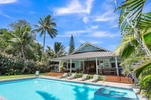 ein Haus mit einem Pool vor einem Haus in der Unterkunft Gorgeous Renovated 1937 Plantation Style Beach House 50 Steps to the Center of the Beach home in Kailua