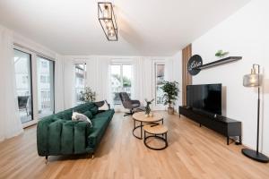 uma sala de estar com um sofá verde e uma televisão em koCASA-Apartments 01, City-Center Böblingen, Stellplatz, Balkon, Waipu-Tv em Böblingen