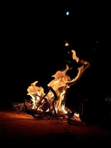 a fire is burning with the moon in the background at Wadi rum view camp in Wadi Rum