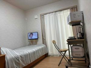 - une chambre avec un lit, une télévision et une fenêtre dans l'établissement Guest House Harukawa, à Osaka