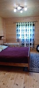 1 dormitorio con 1 cama grande con manta morada en Котедж "Затишний відпочинок", en Huklyvyy