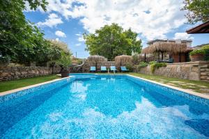 een zwembad met blauw water in een tuin bij Villa Komitata-Pool and Jacuzzi in Balchik