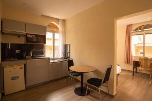 een keuken met een tafel en stoelen in een kamer bij Aparthotel Madeleine in Antananarivo