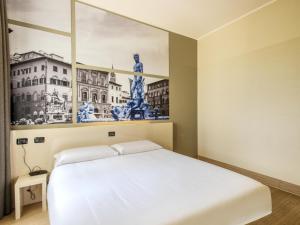 sypialnia z białym łóżkiem i obrazem na ścianie w obiekcie B&B Hotel Firenze Novoli we Florencji