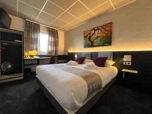 ein Hotelzimmer mit einem großen Bett mit weißer Bettwäsche in der Unterkunft BRIT HOTEL LE VESOUL in Vesoul