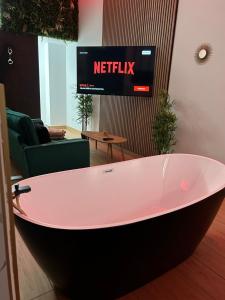 eine große Badewanne in einem Zimmer mit einem TV in der Unterkunft L evazion appartement Grenoble in Grenoble