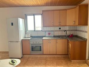 cocina con armarios de madera y nevera blanca en Garza Attic House, en Ojos de Garza