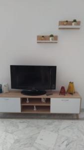 - une télévision à écran plat installée au-dessus d'un centre de divertissement dans l'établissement Appartement slim centre sousse, à Sousse