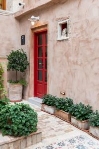 een rode deur aan de zijkant van een gebouw met planten bij Hotel Off in Chania