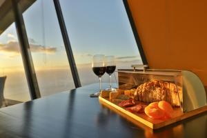 een tafel met een dienblad met eten en twee glazen wijn bij Villa Leonor Cliffside Retreat in Calheta