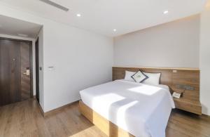 een slaapkamer met een wit bed en houten vloeren bij Green LP Hotel & Apartment in Vung Tau