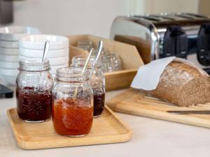 deux bocaux de confiture et une miche de pain sur une planche de découpe dans l'établissement ibis budget Leuven Centrum, à Louvain