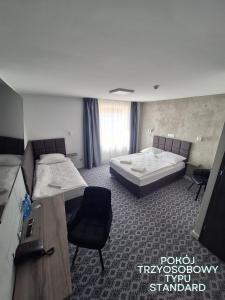 um quarto de hotel com duas camas e uma secretária em Hotel Gordon em Varósvia