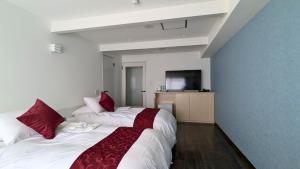 two beds in a hotel room with red pillows at 瀬戸内リゾートホテル in Matsuyama