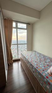 a bedroom with a bed and a large window at Apt Puri Orchard at puri in Jakarta