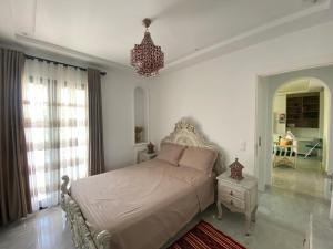 Marsa-Sidi Bousaid Cosy Authentic Apartment في المرسى: غرفة نوم بسرير وثريا