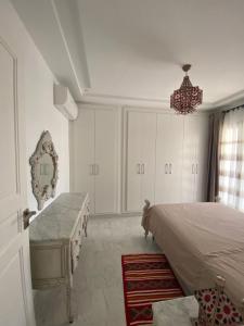 Marsa-Sidi Bousaid Cosy Authentic Apartment في المرسى: غرفة نوم بسرير وطاولة وثريا