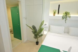 - une chambre avec un lit blanc et une plante en pot dans l'établissement Discover the New and Improved Deep View Studio, à Ras al Khaimah