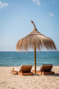 - 2 chaises sous un parasol de paille sur la plage dans l'établissement Estival Centurión Playa, à Cambrils