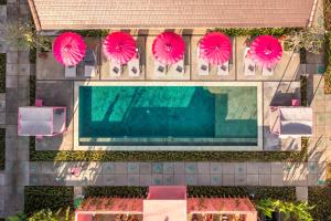 an overhead view of a pool with four pink umbrellas at PinkPrivate Balangan - for Cool Adults Only in Jimbaran